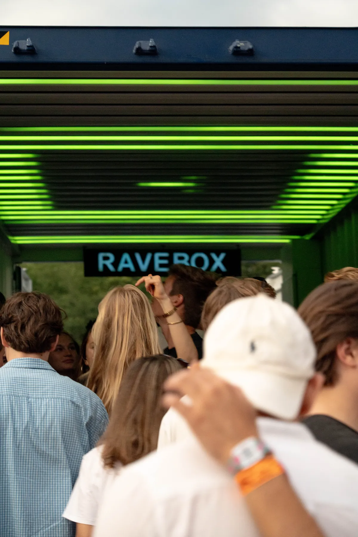 Bezoekers bij de entree van de RAVEBOX container stage onder een groene lichtshow van 60.000 leds